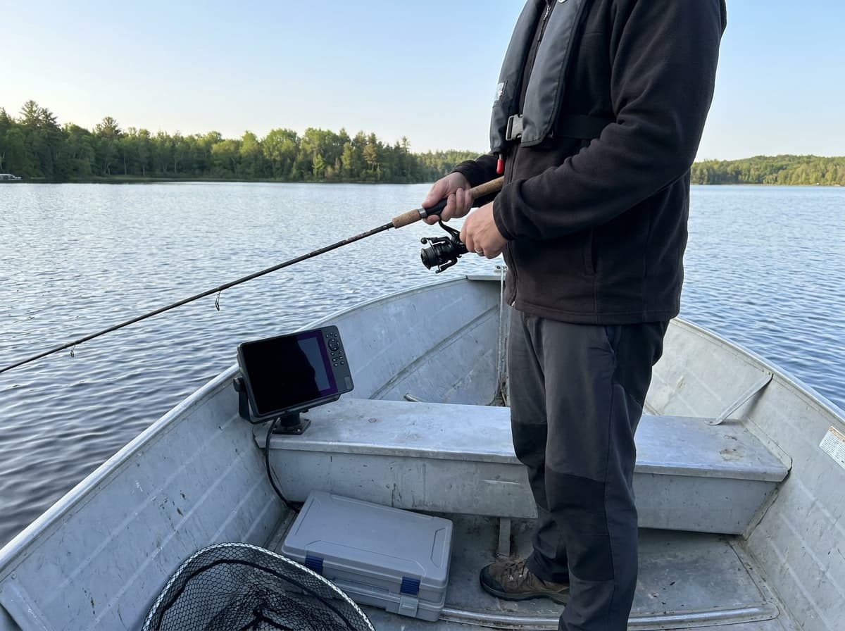Walleye angler working a medium-light spinning setup beside a compact chartplotter